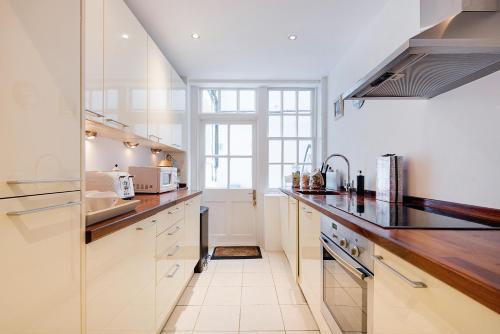 a kitchen with white cabinets and a large window at ARCORE Premium Apartments Broad Court in London