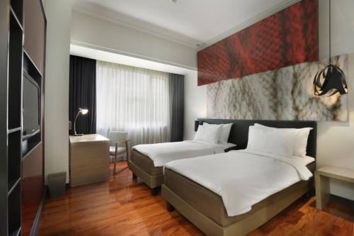 a hotel room with two beds and a television at Malyabhara Hotel - formerly Ibis Malioboro in Yogyakarta