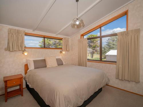 a bedroom with a bed and two windows at Relax On Courtney - Pauanui Holiday Home in Pauanui