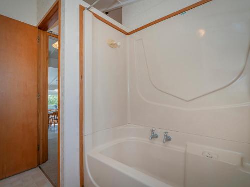 a white bath tub in a bathroom with a mirror at Relax On Courtney - Pauanui Holiday Home in Pauanui