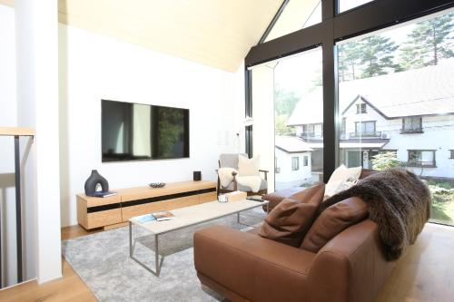 a living room with a couch and a large window at Hérisson - A Valley Chalets Signature Residence in Hakuba