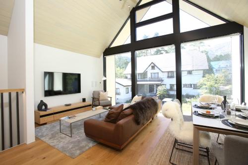 a living room with a couch and a large window at Hérisson - A Valley Chalets Signature Residence in Hakuba