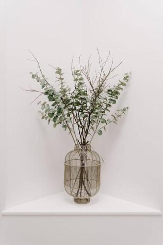 a vase with branches in it sitting on a shelf at Water's Edge in Culburra Beach