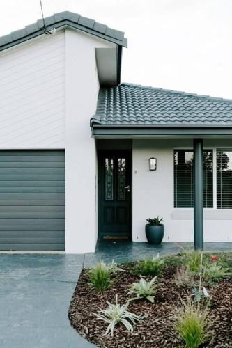 a white house with a black door and a driveway at Water's Edge in Culburra Beach