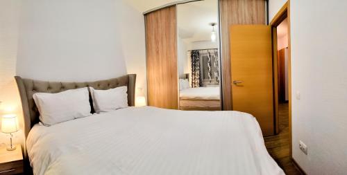 ein Schlafzimmer mit einem großen weißen Bett und einem Spiegel in der Unterkunft My Place in Cluj-Napoca 7 Nights Minimum Stay in Cluj-Napoca