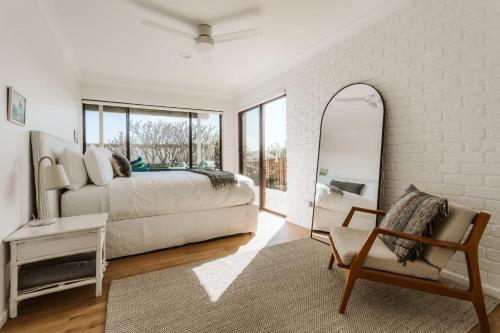 a bedroom with a bed and a mirror and a chair at The G At Gerroa in Gerroa