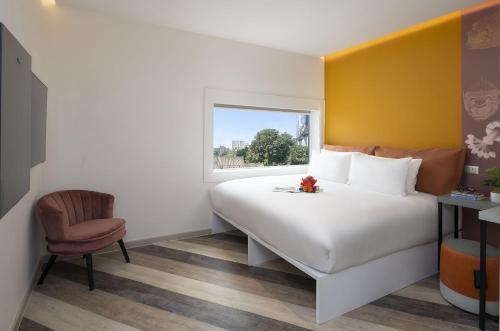 a bedroom with a bed and a chair and a window at Jono Bangkok Asok Hotel in Bangkok