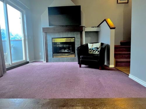 a living room with a fireplace and a chair at Canadian Rockies Chalets by Trilink - 2 & 3 Bedroom Condos - Self Check-In - Walking Distance to Downtown - Free Parking - Pet-Friendly - No AC in Canmore