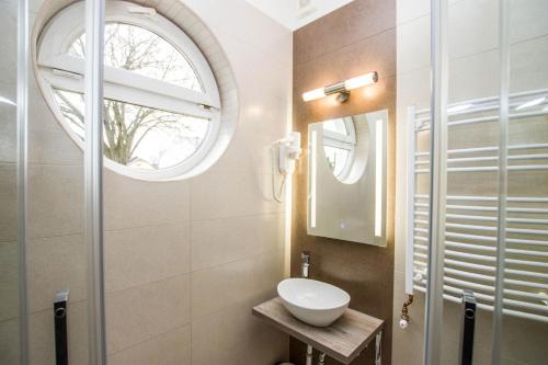 a bathroom with a sink and a round window at Járja Panzió in Hajdúszoboszló