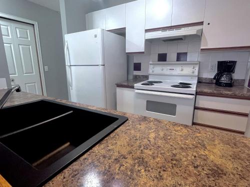 a kitchen with white appliances and a granite counter top at Canadian Rockies Chalets by Trilink - 2 & 3 Bedroom Condos - Self Check-In - Walking Distance to Downtown - Free Parking - Pet-Friendly - No AC in Canmore