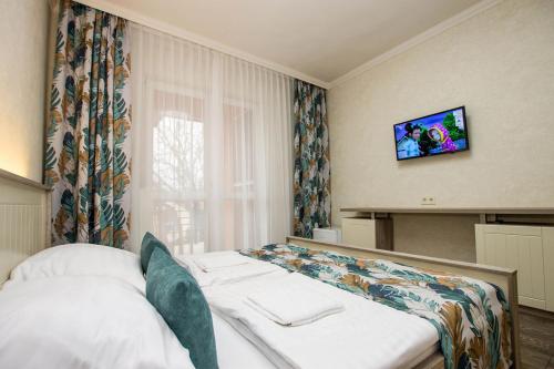 a bedroom with a bed with a television on the wall at Járja Panzió in Hajdúszoboszló