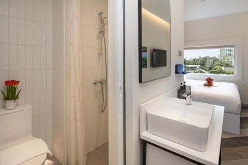a bathroom with a sink and a toilet and a bed at Jono Bangkok Asok Hotel in Bangkok