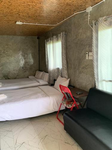 a bedroom with two beds and a red chair at Smile Box Coffee & Resort in Ban Nong Hin
