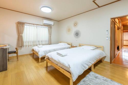 a bedroom with two beds and a table and a window at Traditional house/200sqm/good location/5BR/15Max in Kinugasa