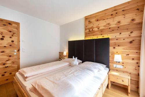 a bedroom with a large bed with a wooden wall at Superior Apartments Marialisa Orchi in Chiusa