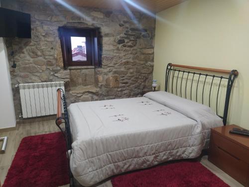een slaapkamer met een bed en een stenen muur bij Aldeia de Moura Morta 