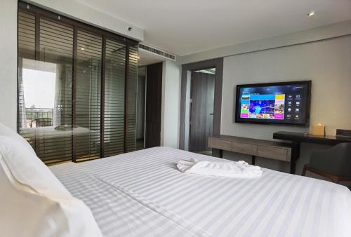 a bedroom with a white bed with a tv on the wall at Citrus Grande Hotel Pattaya by Compass Hospitality in Pattaya South