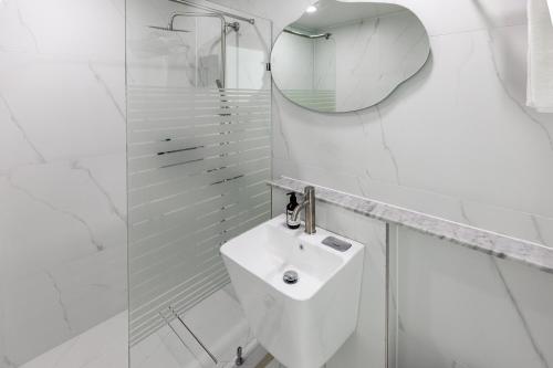 a white bathroom with a sink and a mirror at Aewol Oceanstay in Jeju
