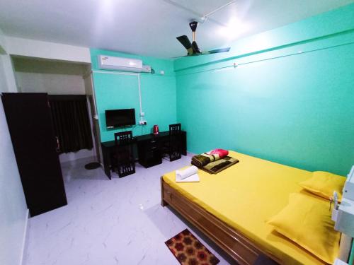 a bedroom with a yellow bed and a green wall at Jungle Eco Mansion in Kāziranga