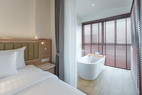 a bedroom with a bed and a bath tub next to a window at Infinity Aonang Krabi in Ao Nang Beach