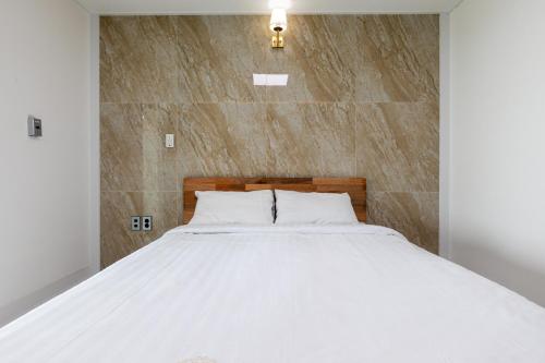 a bedroom with a white bed with a stone wall at Aewol Oceanstay in Jeju
