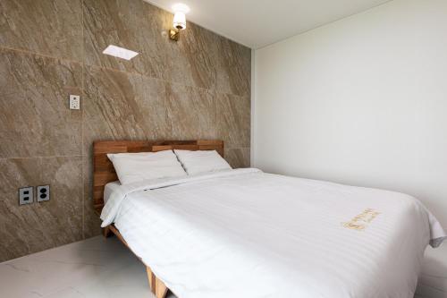 a bedroom with a large bed with white sheets at Aewol Oceanstay in Jeju