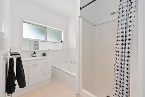 a white bathroom with a sink and a shower at All Beached Out - 8 guests, cental, 450m to beach! in Ocean Grove
