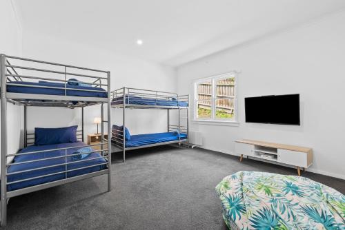 a bedroom with two bunk beds and a flat screen tv at All Beached Out - 8 guests, cental, 450m to beach! in Ocean Grove