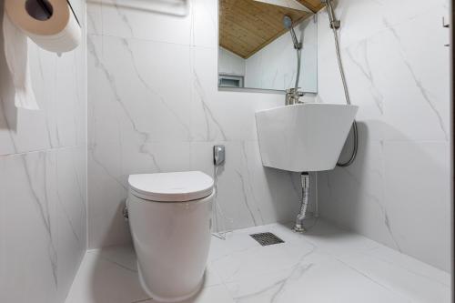 a white bathroom with a toilet and a sink at Aewol Oceanstay in Jeju