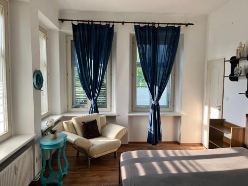 een slaapkamer met blauwe gordijnen, een stoel en een bed bij Arnie Apartman in Arnoldstein