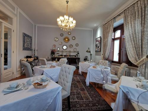 un restaurant avec des tables et des chaises blanches et un lustre dans l'établissement Chalet Vitorino, à Sintra