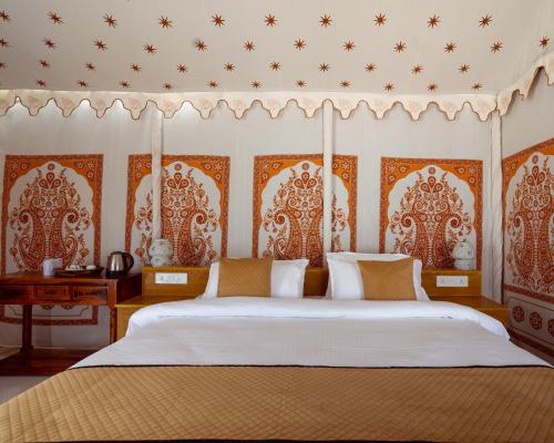 a bedroom with a large bed with an ornate headboard at Real Desert Man Safari Camp in Jaisalmer