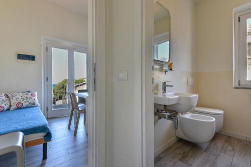 a bathroom with a sink and a toilet and a mirror at Il Quartiere apt Capraia in Pomonte