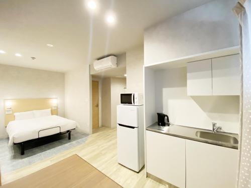 Il comprend une chambre avec un lit et une cuisine avec un évier. dans l'établissement たかのばしホテル Takanobashi HOTEL, à Hiroshima