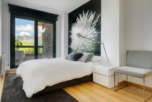 a bedroom with a bed and a chair and a window at Casa LUNA la luna de CuentoGuía in Panticosa