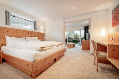 a bedroom with a large bed and a desk at Alpen-Comfort-Hotel Central in Nauders