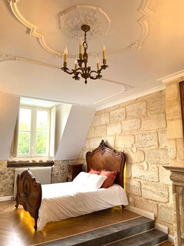 une chambre avec un lit et un lustre dans l'établissement Château Borgeat de Lagrange - privatisation, à Blaye