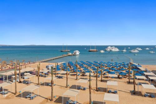 a beach with umbrellas and boats in the water at Pickalbatros Blu Spa Resort - Adults Friendly 16 Years Plus- Ultra All-Inclusive in Hurghada