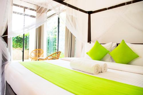 1 dormitorio con 1 cama con almohadas verdes y blancas en Golden Ray villa en Anuradhapura