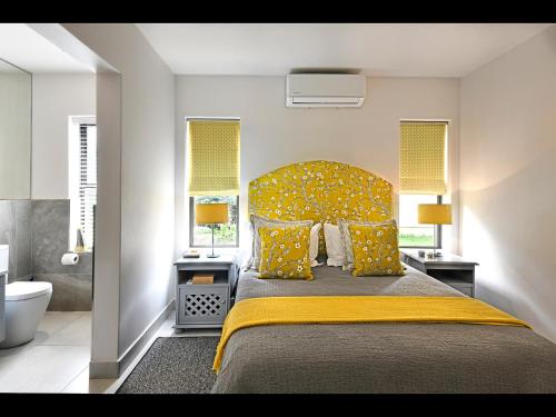 a bedroom with a large bed with a yellow bedspread at Small Wonder in Franschhoek