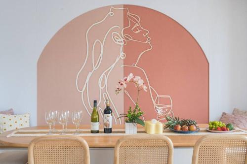 a table with wine glasses and a painting of a woman at Penthouse Hermès in Kuala Lumpur