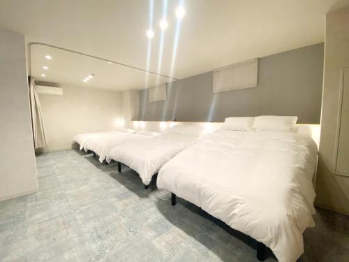 a row of white beds in a room at Takanobashi HOTEL in Hiroshima