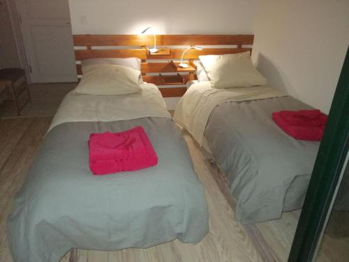 two beds in a hotel room with pink sheets at LES JARDINS CELESTES in Saint-Genest-de-Bauzon
