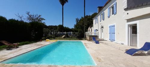 una piscina con 2 sillas y una casa en Chambres d'hôtes dessine-moi un chemin, en Sauvelade