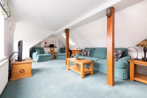 a living room with two blue couches and a tv at The Nest - Cosy Holiday Cottage in Errol