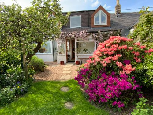 a home with flowers in the yard at The Nest - Cosy Holiday Cottage in Errol