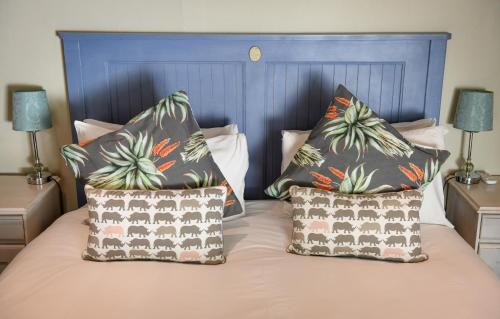 two pillows on a bed with a blue headboard at Cabriere Cottage in Franschhoek