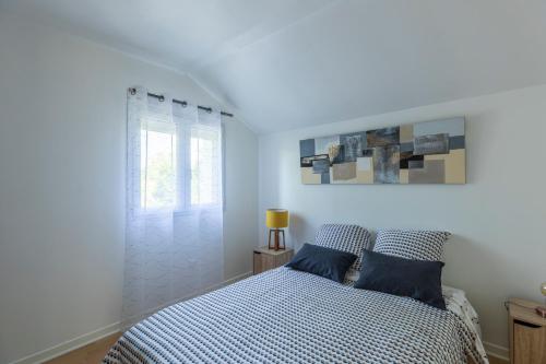 een witte slaapkamer met een bed en een raam bij gite de l'ile ste hélène in Pitres