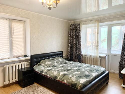 een slaapkamer met een bed in een kamer met ramen bij Аппартаменты в самом центре Площадь-Вал in Chernihiv