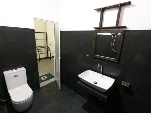 a bathroom with a white toilet and a sink at Luvi Lucas River Side in Weligama